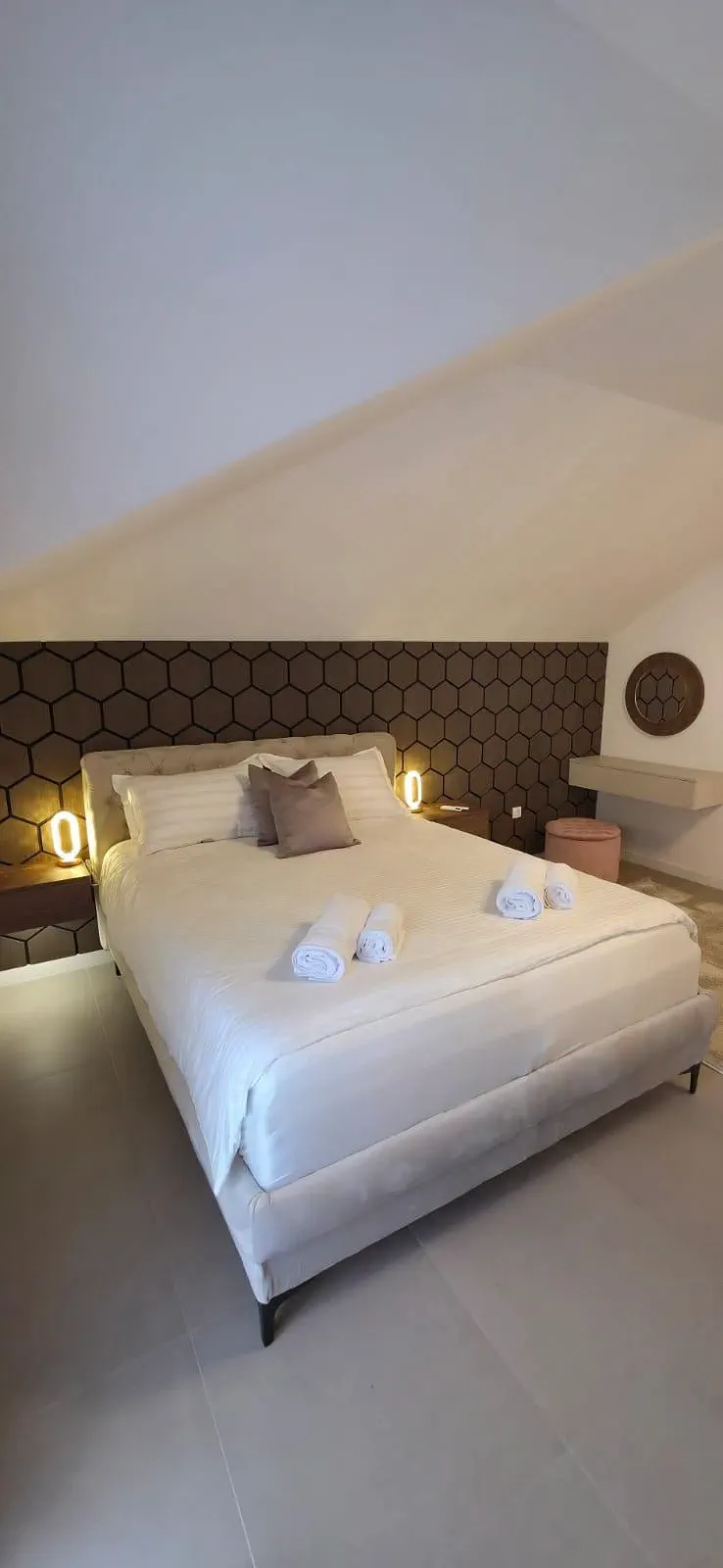 Apartman 4 — bračni krevet sa noćnim lampama uz zid od heksagonalnih panela
