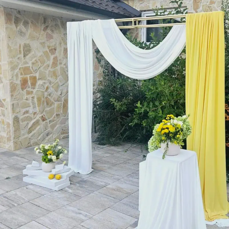 Luk od bijelih i žutih draperija za ceremoniju na otvorenom